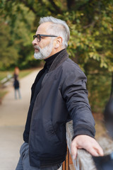 Senior man standing waiting on a bridge