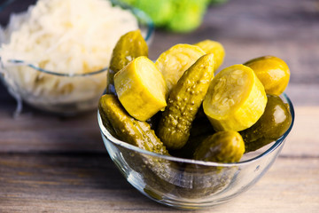 pickled cucumbers and zucchini in a glass plate on a wooden board