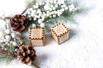 Christmas tree with cones and little snow balls on the snow with wooden digital cubes indicated christmas date