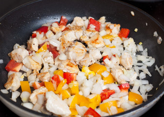 Chicken fillet, bell peppers, onion on frying pan