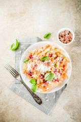 Italian food, fusilli pasta with  tomato sauce, grated parmesan cheese and basil, light stone table...