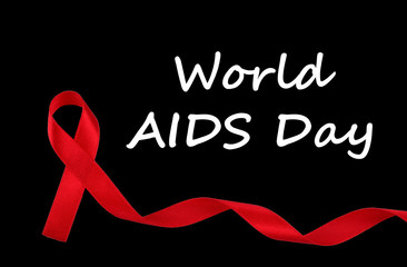 World AIDS Day concept, red ribbon on black background, an international day dedicated to raising awareness of the AIDS