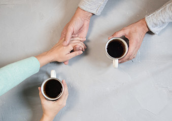 Fototapeta na wymiar Couple in love holding hands with coffee on white marble table. Photograph taken from above, top view with copy space