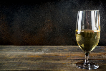 One white wine glass on dark background copy space