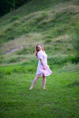 Beautiful girl in summer dress runs in the meadow.