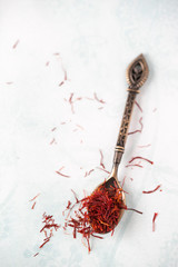 Spoon with saffron threads on light ground