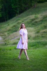 Fototapeta na wymiar Beautiful girl in summer dress runs in the meadow.