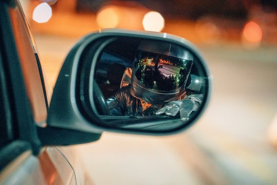 Reflection of spaceman in wing mirror of a car at night