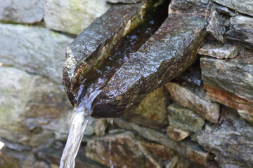 A close view of a stone carved fountain pouring fresh and clean mountain water in the Val d'Otro valley, Alps mountains, Piedmont, Italy