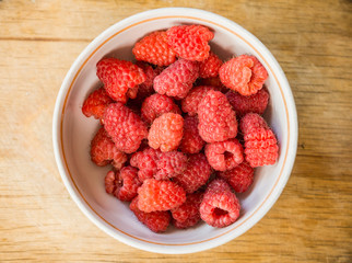Freshly harvested ripe raspberries in bowl. Selective focus.