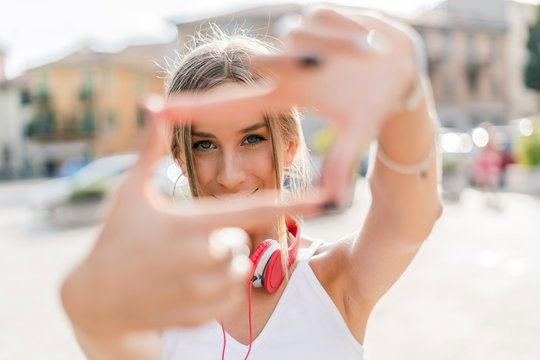 Portrait of smiling teenage girl making a finger frame in the city