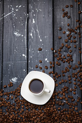 coffee pours into a Cup on a black wooden table with coffee beans