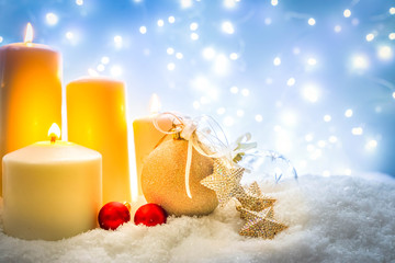 White christmas - burning advent candles in snow , blue night with lights in background, retro toned