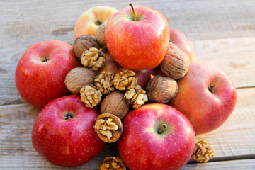 Red apples and wainuts on wooden table