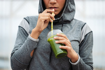Detail of sporty woman taking a rest for drinking nutritive detox smoothie. Fitness nutrition and outdoor workout concept.