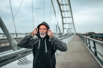 Portrait of a senior sportsman in hoodie outdoors.