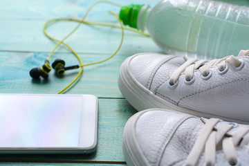 Sports accessories - krassovki (sneakers), a bottle of water, a phone with headphones. Health and sport.