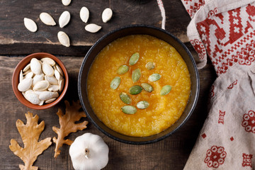 Pumpkin soup in the bowl on a wooden table. Rustic still life.