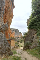 The Barranco de la Hoz Seca (Dry Defile Gully) canyon, with scarps, bushes and red rocks, in a cloudy atumn, in the Jaraba rural town, Aragon, Spain