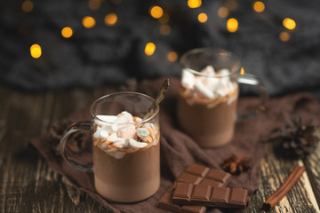 Hot chocolate with cinnamon sticks, anise, nuts and cocoa powder on a rustic wooden background,...