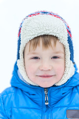 Outdoor portrait face of a little boy in a cap close-up in on the background snow winter