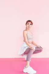 young stylish female athlete in visor hat posing on pink