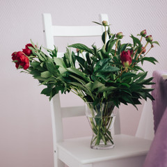 bouquet of red peonies in a vase on the white chair, wedding decoration