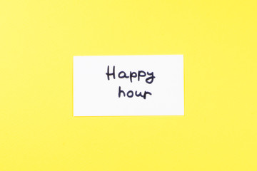 Happy hour text on a white paper on a yellow background.
