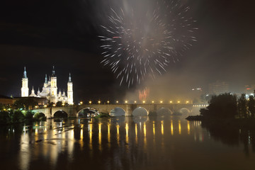 Fototapeta na wymiar The fireworks during the 2018 Pilar festival next to the Pilar Cathedral and the Stone Bridge over the Ebro river, in Zaragoza, Aragon region, Spain