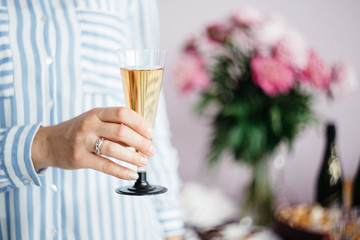 women's hand holding a glass of champagne on the background of the festive table