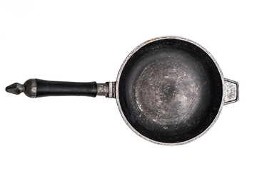 Empty old cast iron frying pan on white surface with cracked paint background