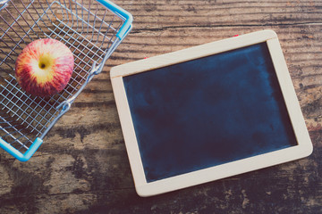 blackboard next to shopping cart with healthy fruit and copyspace