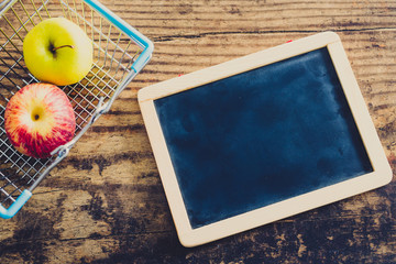 blackboard next to shopping cart with healthy fruit and copyspace
