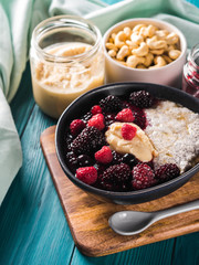 Vegan cashew milk Chia pudding with berries and home made almond butter served in a bowl on wooden board