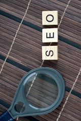 SEO, Search Engine Optimization word collected of wooden elements with the letters and also magnifying glass.