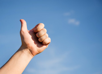 The Thumbs Up, the man's fist with a thumb on a blue background