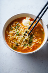 Easy japanese ramen with noodles, pork broth, egg and leek in white bowl on concrete background