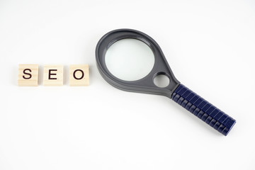 SEO, Search Engine Optimization word collected of wooden elements with the letters and also magnifying glass.