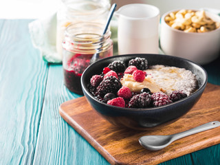 Vegan cashew milk Chia pudding with berries and home made almond butter served in a bowl on wooden board
