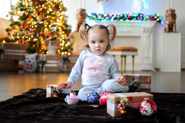 Ребенок ждет чуда в Новый год. С новым годом! Счастливого Рождества! Новогодняя елка с рождественскими игрушками. Девочка  с подарками.
