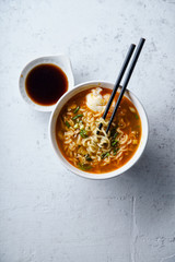 Overhead image of easy japanese ramen with noodles, pork broth, egg and leek in white bowl on concrete background