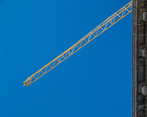 Fototapeta premium Construction crane tower on blue sky background. Crane and building working progress. 