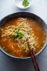 Easy japanese ramen with noodles, pork broth, egg and leek in handmade blue ceramic bowl with wooden chopsticks. Concrete background