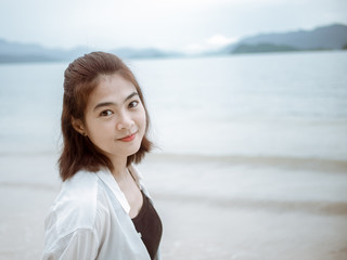 Asian girl looking over shoulder while standing on tropical beach. Portrait of happy young woman smiling at sea. sweet smile. Vintage Tone. copy space...
