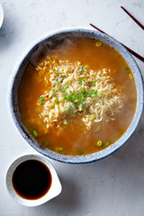Top view picture of easy japanese ramen with noodles, pork broth, egg and leek in handmade blue ceramic bowl with wooden chopsticks. Concrete background