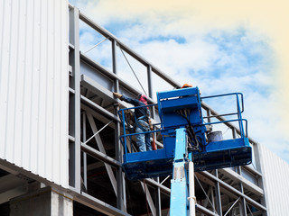 Construction worker at construction site using lifting boom machinery