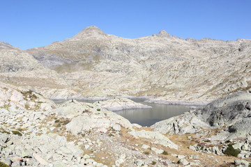 The upper Balchimaña artificial lake, among barren rocky mountains and a blue sky in a sunny autumn, in Panticosa, Aragon Pyrenees, Spain