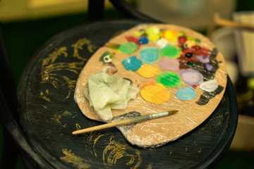 Dirty colorful artists palette on cardboard for mixing vibrant oil colors, dark wooden background. Art hobby, expression, creative leisure concepts