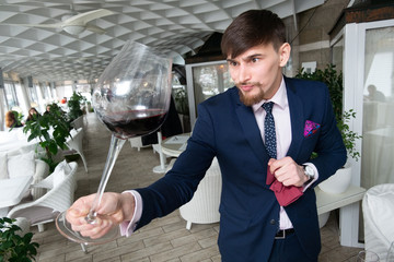 young male sommelier holds a glass of red wine while tasting wine