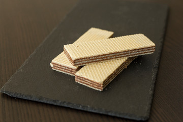 Wafers with chocolate on black slate board, close-up